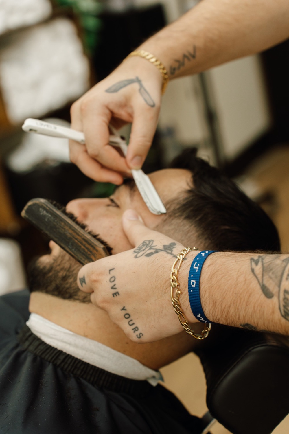 A barber at The Avenue lining up a client's hairline with a straight razor